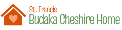 St. Francis Budaka Cheshire's logo with the text written in red and green text. Next to the text is the logo graphic featuring a silhouette of a red house with a pink heart inside.